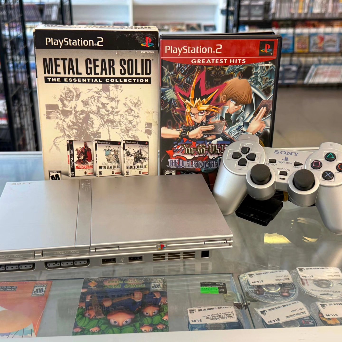 PlayStation 2 Slim console with Metal Gear Solid Essential Collection, Yu-Gi-Oh, and DualShock controller